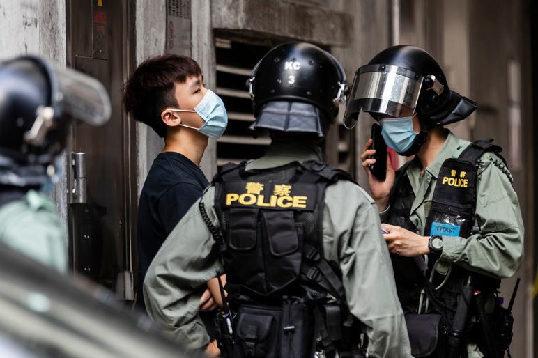 Riot police stop and search pedestrian during a protest in Hong Kong, China